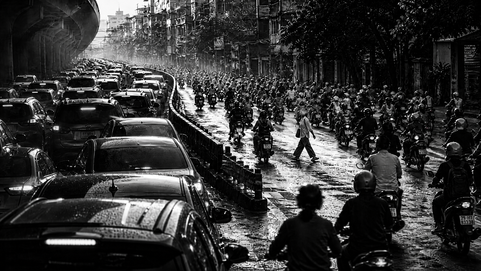 Black-and-white street scene with gridlocked cars beside a flowing stream of scooters in Saigon traffic.